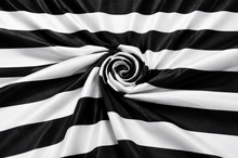 Black and white horizontally striped fabric draped in a spiral pattern, showing a smooth satin-like sheen.