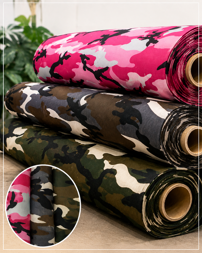 Three rolls of camouflage fabric stacked together, with a circular inset showing a close-up of the pink camouflage pattern. The rolls feature different camouflage designs including pink, black, gray, green, and beige.