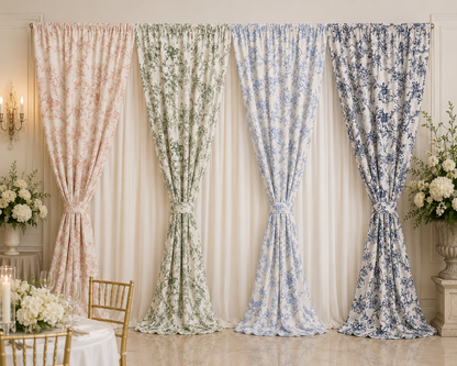 Four elegant floral curtains in soft pastel shades of pink, sage green, light blue, and navy blue, hung in a row on a gold rod against a cream background with decorative floral arrangements and a dining table.