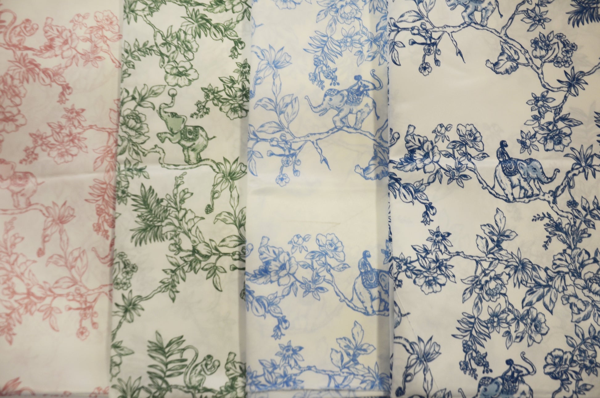 A collection of satin print drapery panels displayed in three rows, with the top row featuring a red floral pattern, the middle row a blue floral pattern, and the bottom row a green floral pattern. Each panel is folded to show both sides of the fabric.