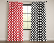 Two checkered curtain panels hanging on a black rod in front of a window. The left panel is red and white checkered, and the right panel is black and white checkered.