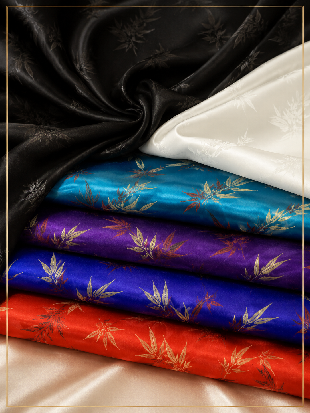 Four folded satin fabrics in black, white, turquoise blue, purple, and red, each printed with a gold-toned bamboo leaf pattern, arranged on a beige satin surface.