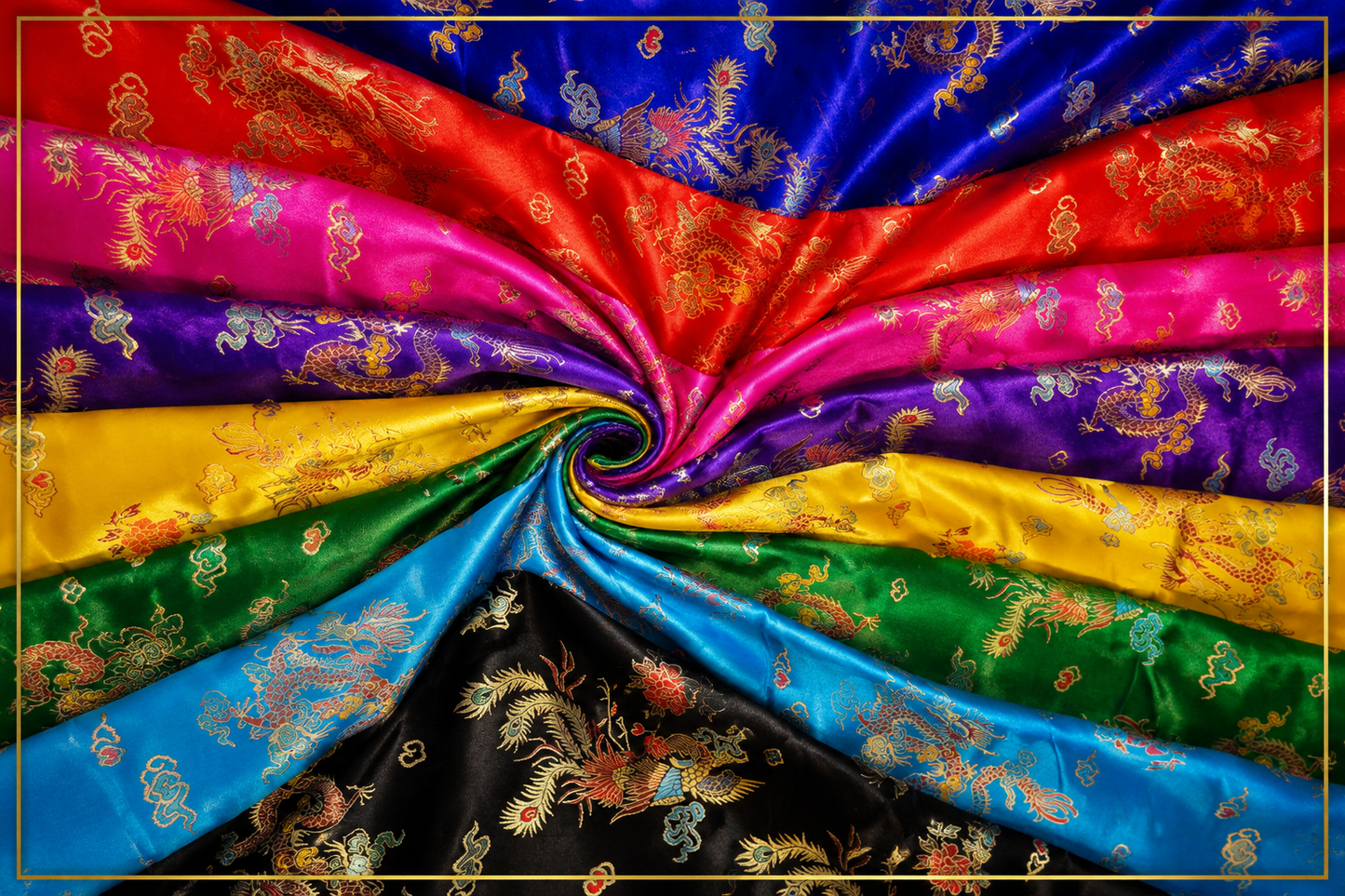 A close-up of draped satin fabric arranged in a spiral, showing multiple colors including blue, red, pink, purple, yellow, green, and black, each with gold dragon and cloud motifs.