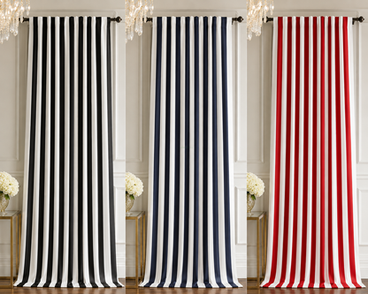 Three curtain panels with vertical stripes are displayed side by side in an interior room setting. The left panel is black and white, the middle panel is navy and white, and the right panel is red and white.