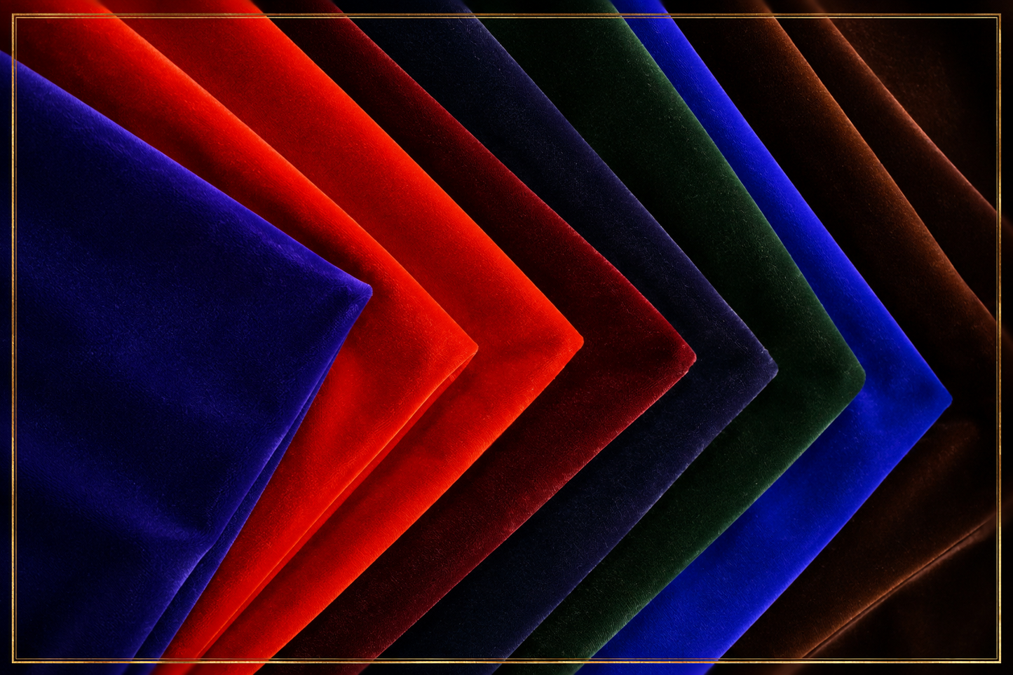 A stack of velvet fabric squares fanned out in a V-shape arrangement, showing different colors: dark brown, royal blue, forest green, navy, red, and bright royal blue, set against a dark background with a thin gold border.